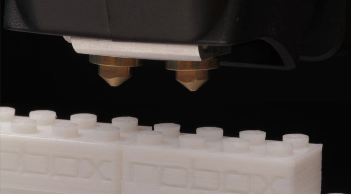 Closeup of the printer head and 3D printed Lego-like construction blocks